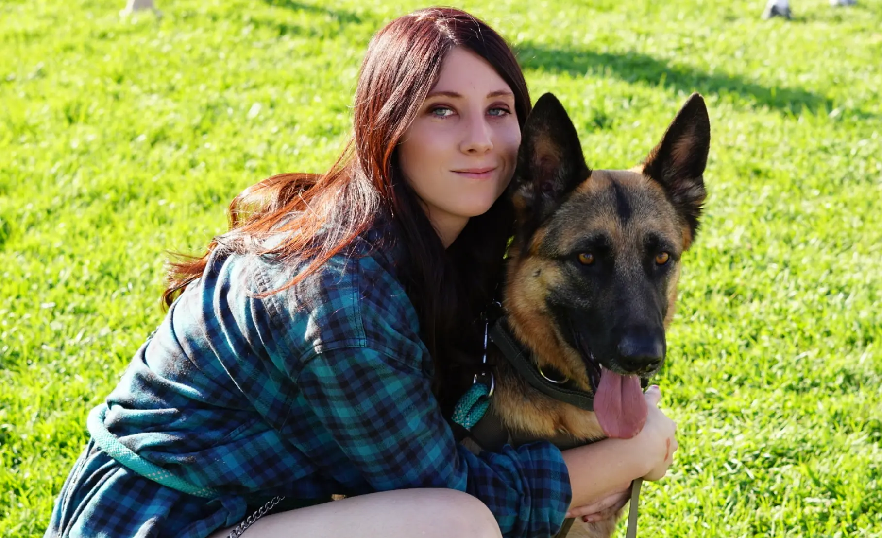 Emily, lead trainer, sitting in the grass with her Belgian Malinois at Hasley Canyon Ranch K9 Training in Castaic, CA